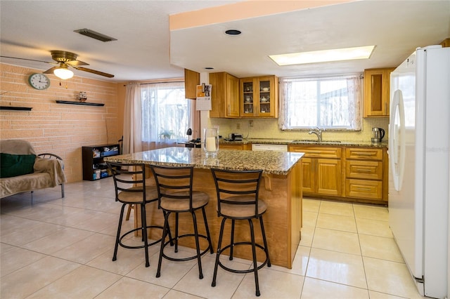 kitchen featuring a center island, light stone counters, white appliances, and light tile patterned floors