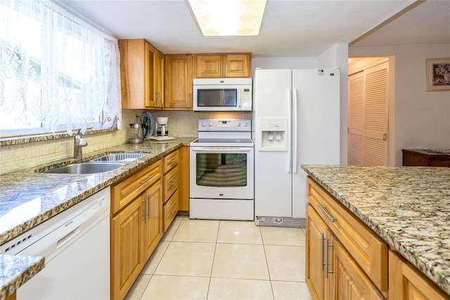 kitchen featuring light tile patterned flooring, sink, white appliances, light stone countertops, and backsplash