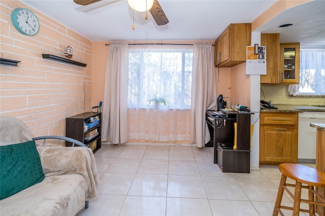 kitchen featuring brick wall, dishwasher, decorative backsplash, light tile patterned floors, and light stone counters