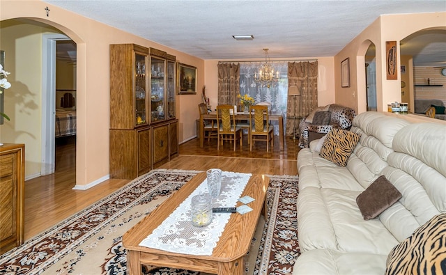 living room featuring a notable chandelier, wood-type flooring, and a textured ceiling