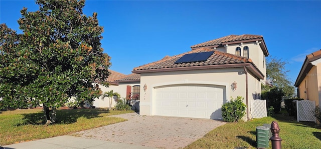 mediterranean / spanish home with a garage, a front yard, and solar panels