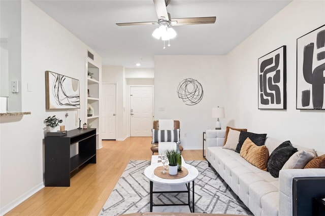 living room featuring ceiling fan, built in features, and light wood-type flooring