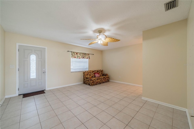 entryway with light tile patterned floors, visible vents, baseboards, ceiling fan, and a textured ceiling