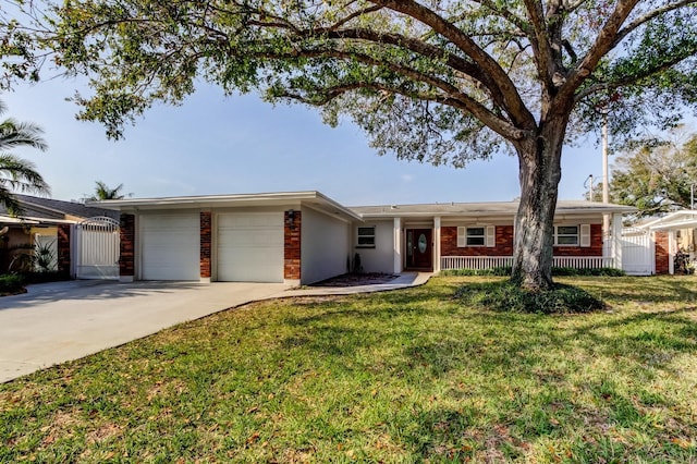 single story home featuring driveway, brick siding, an attached garage, a gate, and a front yard