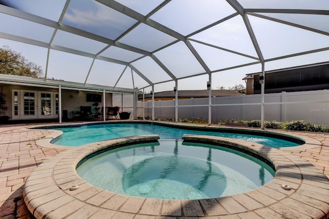 view of swimming pool featuring a pool with connected hot tub, a patio, french doors, and fence