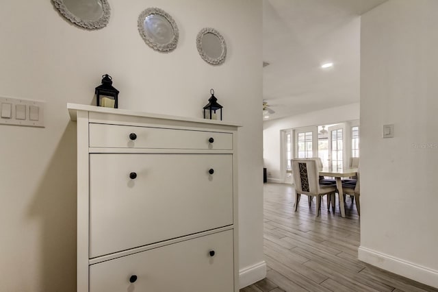 hall with light wood-style flooring and baseboards