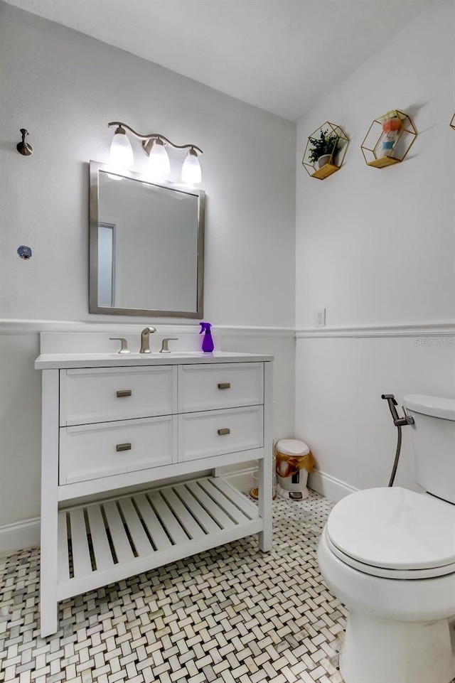 half bathroom featuring tile patterned flooring, baseboards, vanity, and toilet