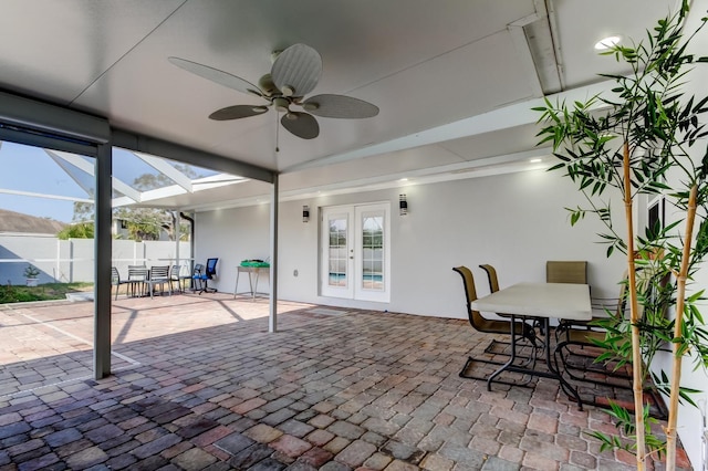 view of patio featuring ceiling fan, glass enclosure, fence, french doors, and outdoor dining space