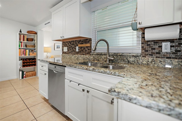 kitchen with white cabinetry, sink, stainless steel dishwasher, light tile patterned floors, and light stone counters