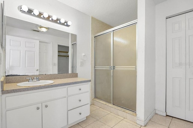 bathroom with walk in shower, tile patterned floors, vanity, and a textured ceiling