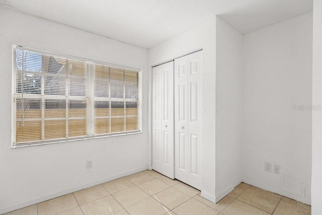 unfurnished bedroom featuring light tile patterned floors and a closet