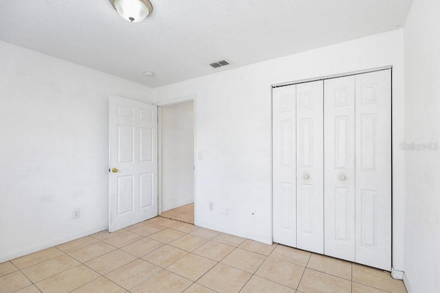 unfurnished bedroom featuring light tile patterned flooring and a closet