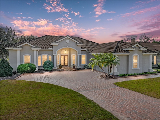 view of front of property featuring a garage, french doors, and a lawn