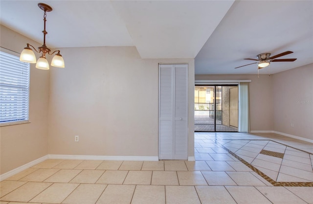 tiled empty room with ceiling fan with notable chandelier