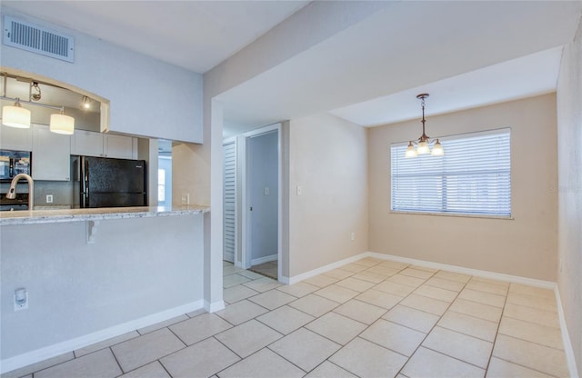 kitchen featuring black refrigerator, a breakfast bar, white cabinetry, sink, and hanging light fixtures