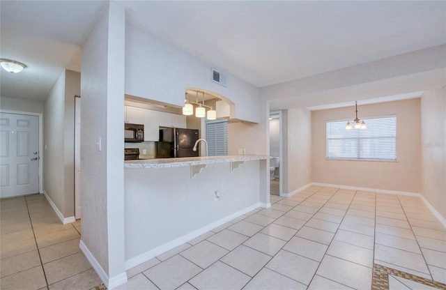 kitchen featuring white cabinetry, black appliances, a kitchen bar, decorative light fixtures, and kitchen peninsula