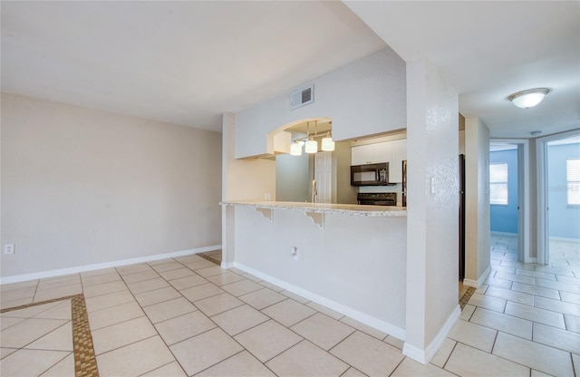 kitchen with light tile patterned floors, sink, white cabinetry, a kitchen breakfast bar, and kitchen peninsula