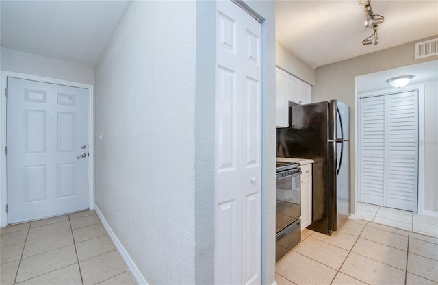 kitchen with rail lighting, light tile patterned floors, electric range oven, and white cabinets