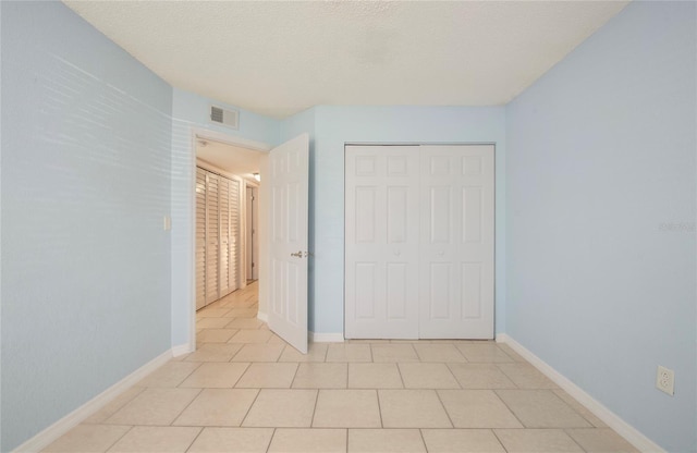 unfurnished bedroom with a closet, a textured ceiling, and light tile patterned flooring