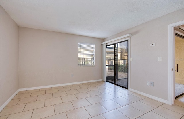 empty room with a textured ceiling and light tile patterned flooring