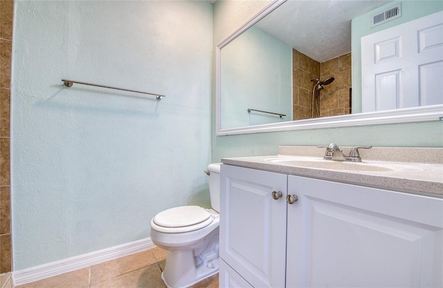 bathroom featuring tile patterned floors, toilet, vanity, and a tile shower