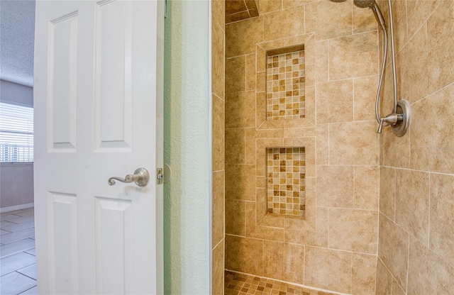 bathroom with a tile shower and tile patterned flooring