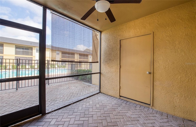 unfurnished sunroom with ceiling fan