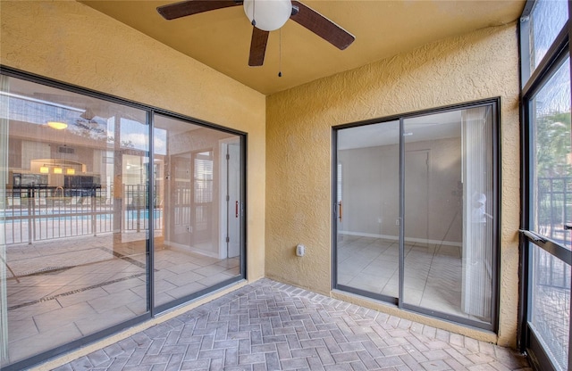 unfurnished sunroom featuring ceiling fan