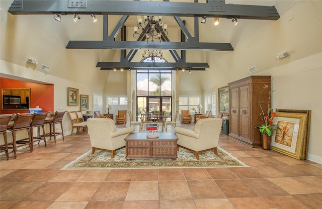 tiled living room featuring an inviting chandelier, rail lighting, and high vaulted ceiling