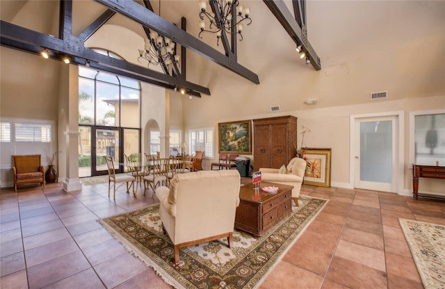 tiled living room with track lighting, a chandelier, and a high ceiling