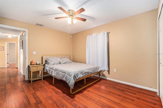 bedroom featuring ceiling fan, dark hardwood / wood-style flooring, and a textured ceiling