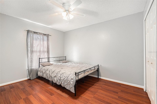 bedroom with ceiling fan, a closet, dark hardwood / wood-style floors, and a textured ceiling