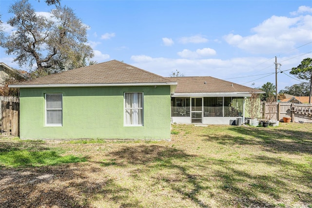 rear view of house featuring a sunroom and a lawn