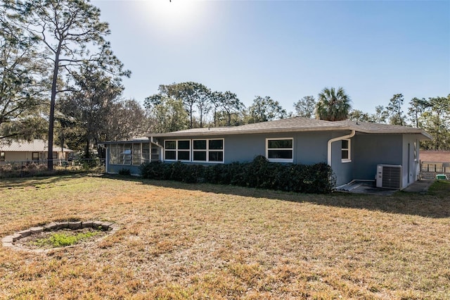 back of property featuring a sunroom, central AC, and a lawn