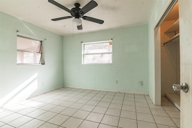 empty room featuring a healthy amount of sunlight, light tile patterned floors, and ceiling fan