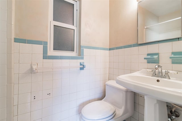 bathroom with toilet, sink, and tile walls