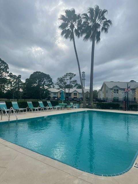 community pool with a patio area and fence