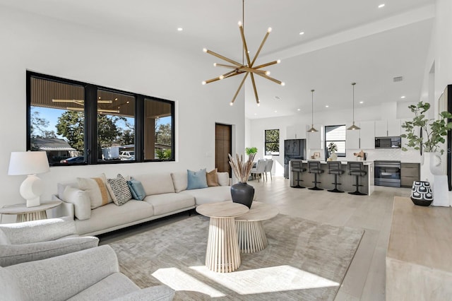 living room featuring a towering ceiling, a chandelier, and light hardwood / wood-style flooring