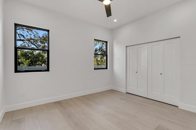 unfurnished bedroom featuring ceiling fan, a closet, and light wood-type flooring