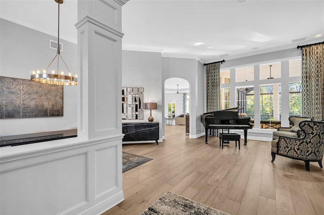 interior space with light wood-type flooring, crown molding, and a chandelier