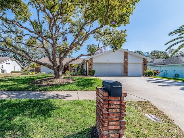 view of front of property featuring a garage, a front yard, brick siding, and driveway