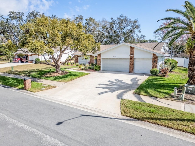 view of front of home featuring brick siding, fence, concrete driveway, a front yard, and a garage