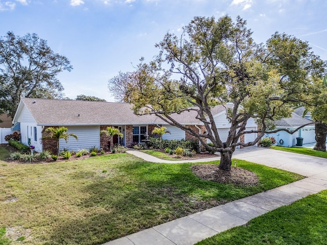 ranch-style home featuring a front lawn, fence, brick siding, and driveway