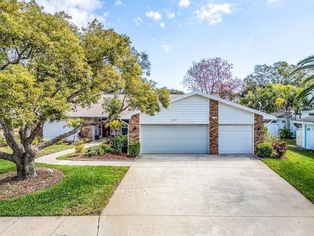 view of front of home featuring a front yard, a garage, brick siding, and driveway