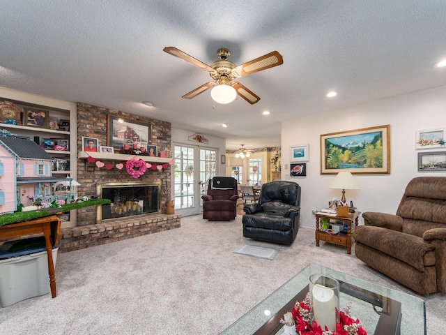 living area with a ceiling fan, a textured ceiling, a brick fireplace, and carpet flooring