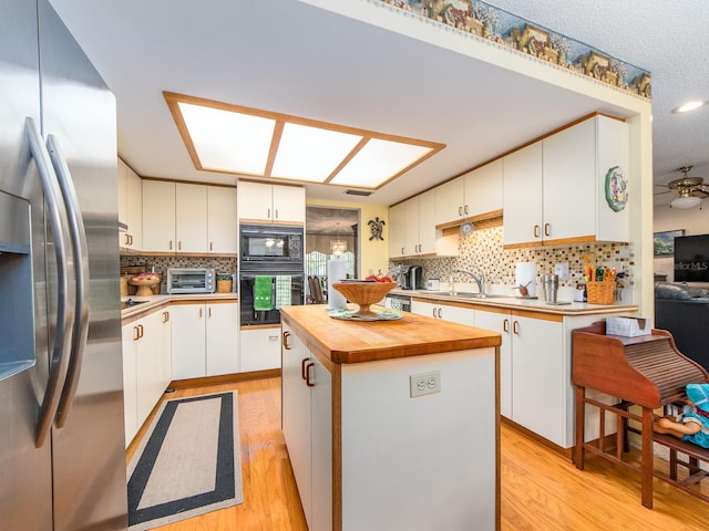 kitchen featuring white cabinetry, black appliances, light wood-style floors, and a sink