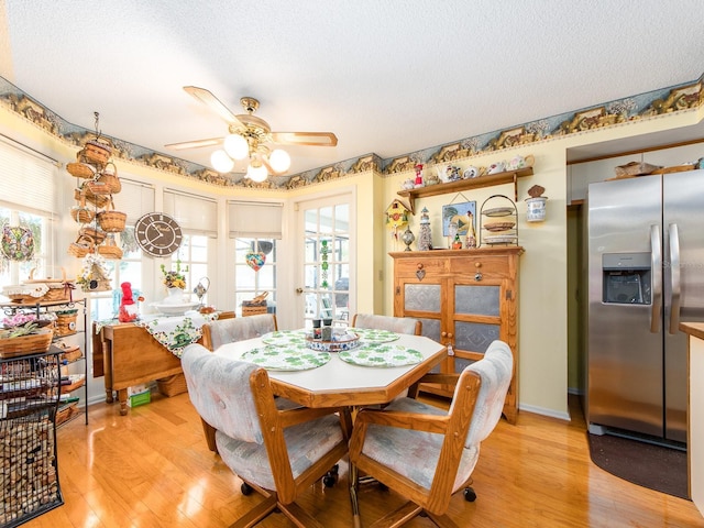 dining room with a ceiling fan, baseboards, light wood finished floors, and a textured ceiling