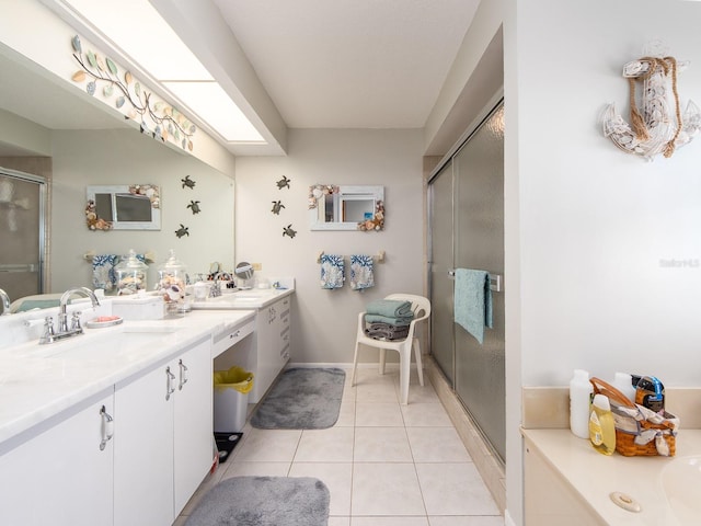 full bathroom with tile patterned flooring, two vanities, a stall shower, a skylight, and a sink