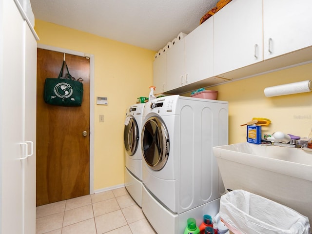 laundry area with a sink, cabinet space, light tile patterned flooring, and washing machine and clothes dryer