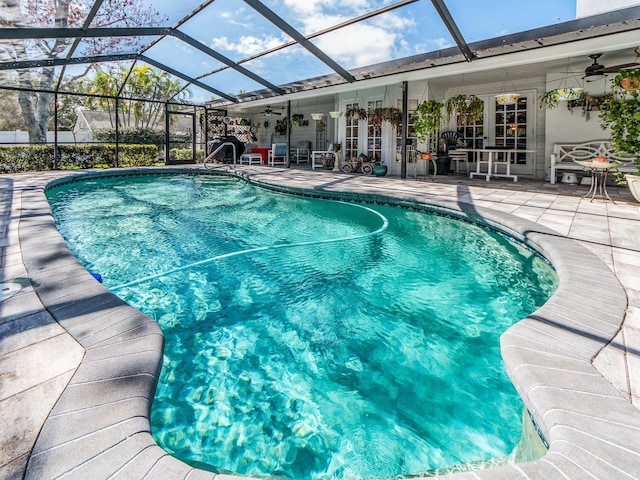 pool with glass enclosure, a patio, and ceiling fan